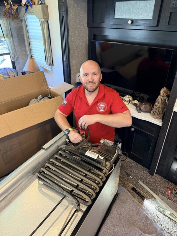 Nick Hastings, owner of Bud's Total RV Care, performing on-site RV repair inside a customer's RV